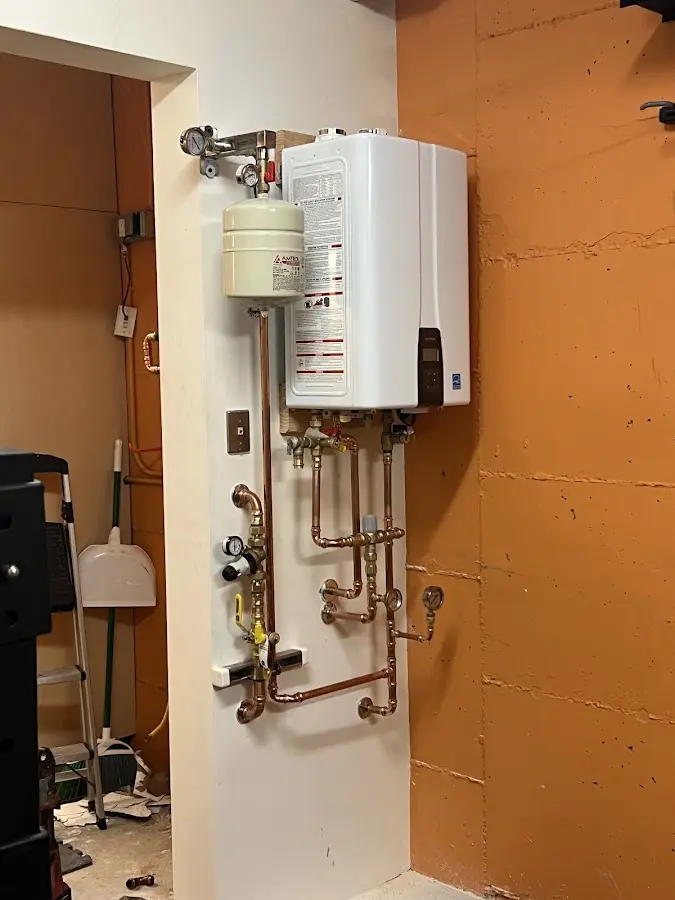 Plumbing technician inspecting water heater connections in Chaska